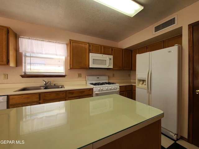 10812 Sandy Koufax Dr, El Paso, TX 79924 - kitchen with a sink, white appliances, light countertops, brown cabinetry, and visible vents