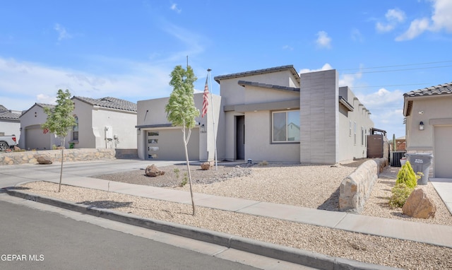 contemporary house with concrete driveway, a tiled roof, an attached garage, and stucco siding
