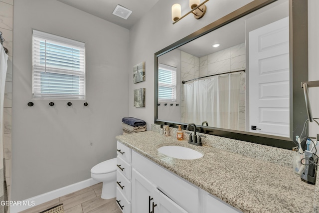 full bath with vanity, toilet, baseboards, visible vents, and tiled shower