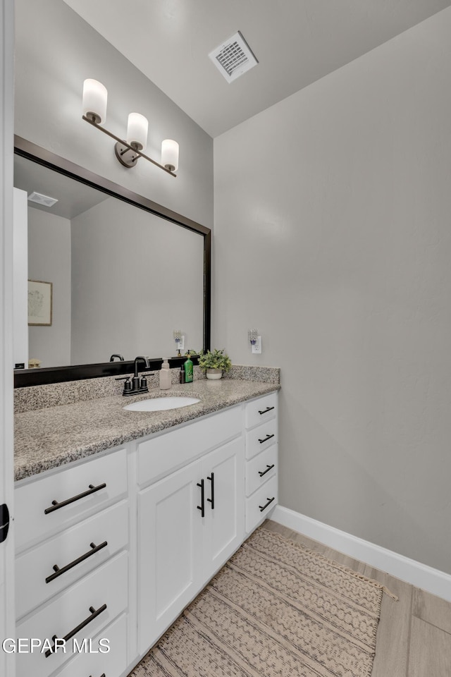 bathroom with vanity, baseboards, wood finished floors, and visible vents