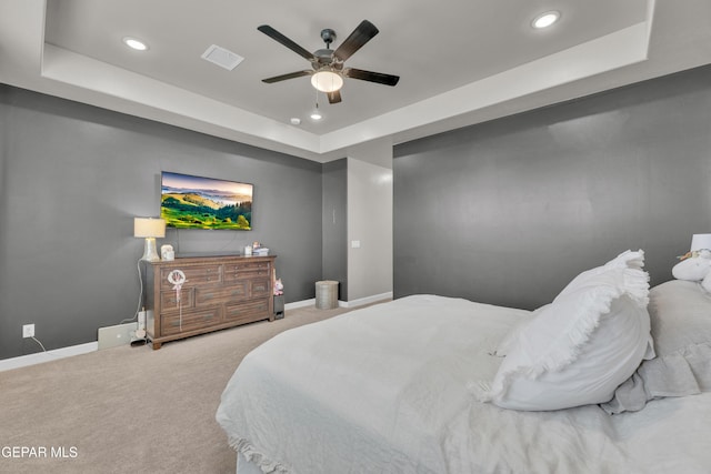 carpeted bedroom featuring recessed lighting, baseboards, visible vents, and a tray ceiling