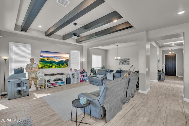 living area featuring visible vents, wood finished floors, baseboards, a raised ceiling, and beamed ceiling