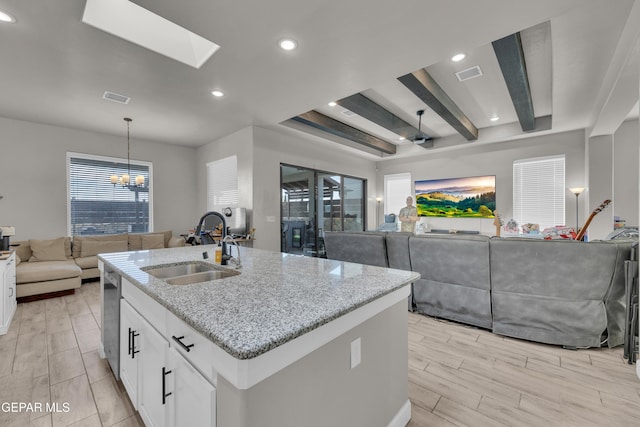kitchen with a sink, visible vents, light stone countertops, and open floor plan