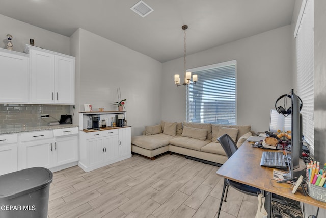 living area with visible vents, light wood-style flooring, and a chandelier