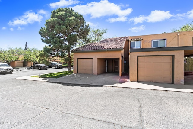 view of property with a garage, stucco siding, and a tile roof