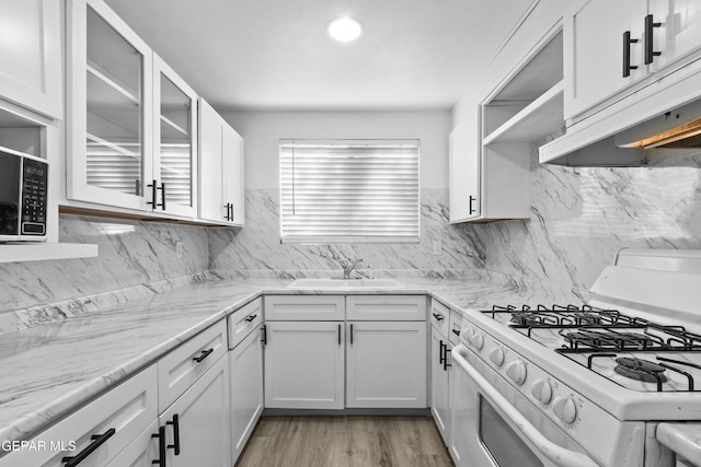 kitchen featuring white cabinets, open shelves, a sink, white gas stove, and under cabinet range hood