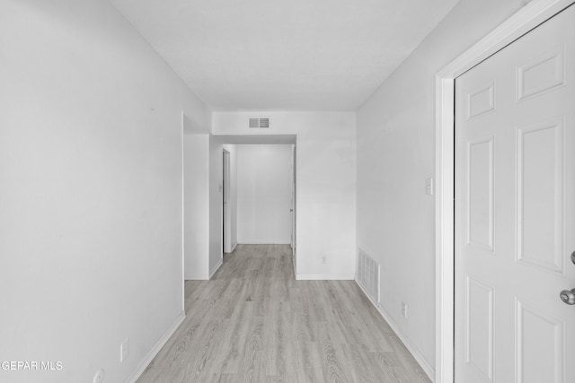 hall with visible vents, light wood-style floors, and baseboards