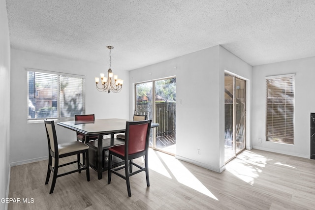 dining room with an inviting chandelier, baseboards, a textured ceiling, and wood finished floors