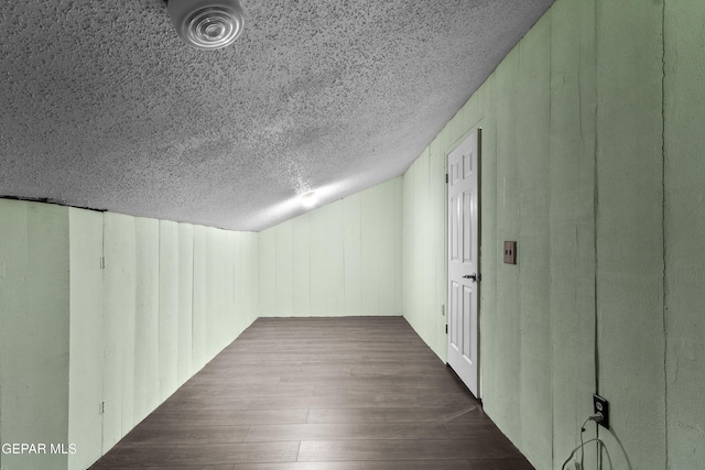 additional living space with dark wood-style flooring and a textured ceiling