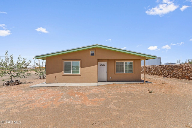back of property with a patio and stucco siding