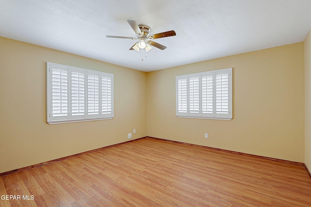 spare room with a ceiling fan, baseboards, and wood finished floors