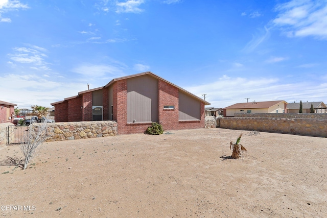 view of side of property with brick siding and fence
