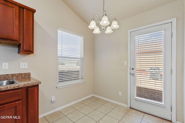 unfurnished dining area with light tile patterned flooring, an inviting chandelier, a sink, baseboards, and vaulted ceiling