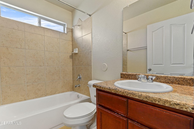 full bathroom with toilet, a textured wall, washtub / shower combination, and vanity
