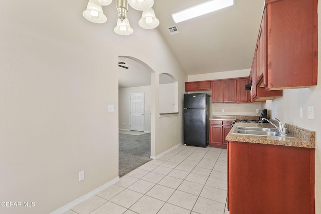 kitchen featuring light tile patterned flooring, a sink, arched walkways, freestanding refrigerator, and visible vents
