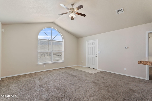 unfurnished room with ceiling fan, light colored carpet, baseboards, vaulted ceiling, and visible vents
