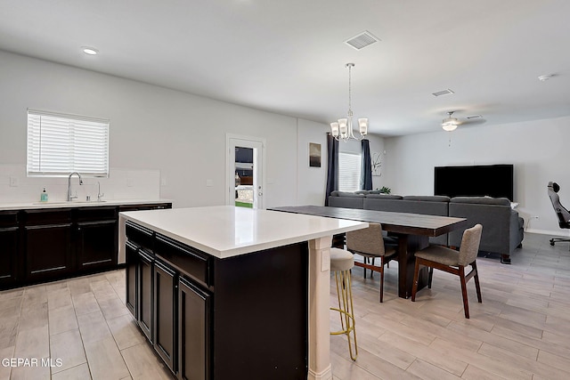 kitchen with an inviting chandelier, open floor plan, a breakfast bar area, light countertops, and a sink
