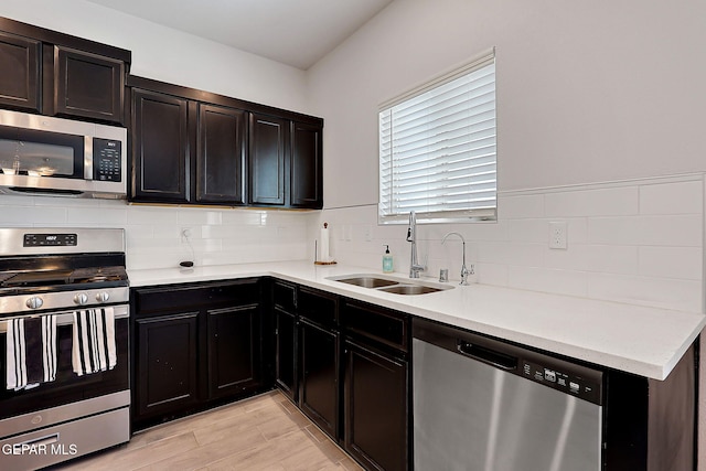 kitchen with backsplash, appliances with stainless steel finishes, a sink, and light countertops