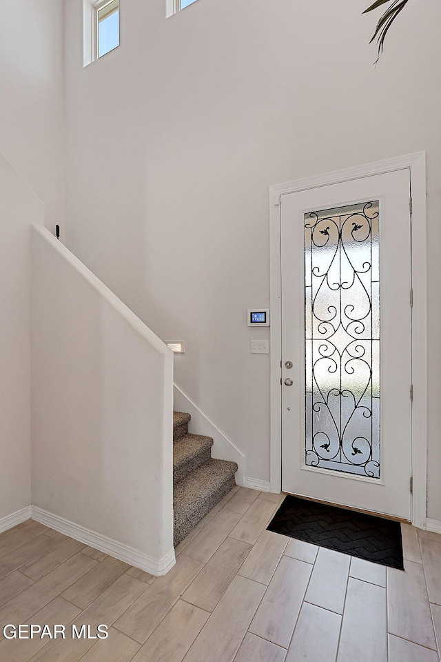 entryway with baseboards, wood tiled floor, and stairs