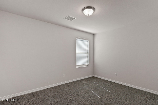 empty room with baseboards, visible vents, and dark carpet