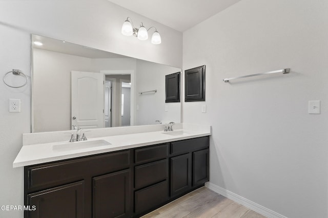 full bathroom featuring baseboards, a sink, wood finished floors, and double vanity