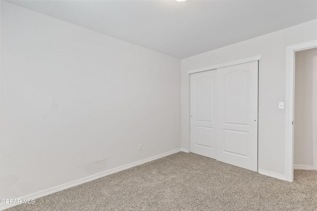 unfurnished bedroom featuring baseboards, carpet flooring, and a closet