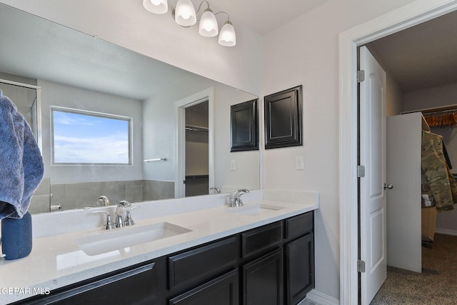 full bathroom featuring double vanity, a walk in closet, and a sink
