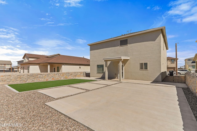 back of house featuring fence private yard, a gate, stucco siding, and a patio
