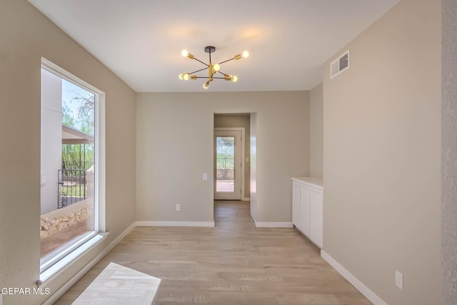 1721 Villa Santos Cir, El Paso, TX 79935 - unfurnished room with visible vents, light wood finished floors, a healthy amount of sunlight, and an inviting chandelier