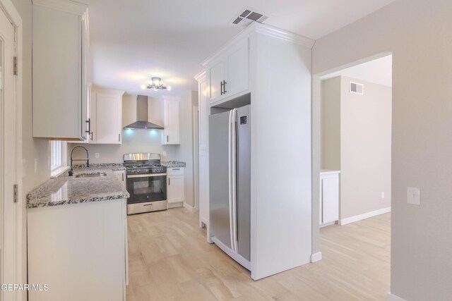 1721 Villa Santos Cir, El Paso, TX 79935 - kitchen with wall chimney range hood, stainless steel appliances, a sink, and light wood-type flooring