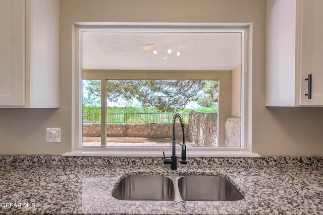 1721 Villa Santos Cir, El Paso, TX 79935 - kitchen featuring white cabinetry, light stone countertops, a healthy amount of sunlight, and a sink