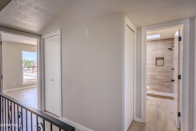 1721 Villa Santos Cir, El Paso, TX 79935 - hall featuring a textured ceiling, baseboards, and light wood finished floors