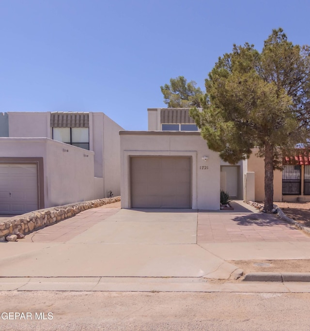 1721 Villa Santos Cir, El Paso, TX 79935 - pueblo-style home with an attached garage, driveway, and stucco siding