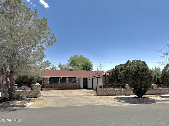 view of front of property with an attached garage, a fenced front yard, brick siding, and driveway
