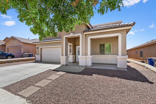 mediterranean / spanish-style house with a garage, a tiled roof, driveway, and stucco siding