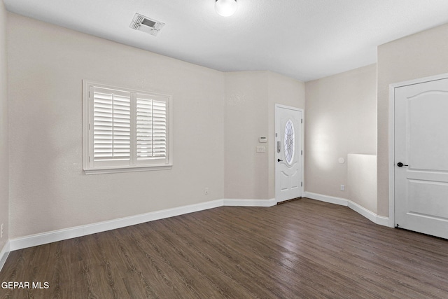 spare room featuring baseboards, visible vents, and dark wood-type flooring