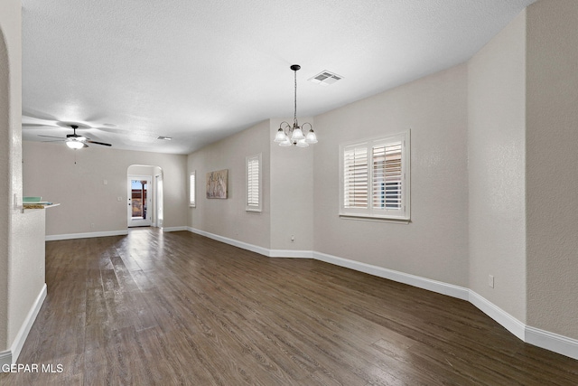 unfurnished room featuring visible vents, arched walkways, dark wood finished floors, baseboards, and ceiling fan with notable chandelier