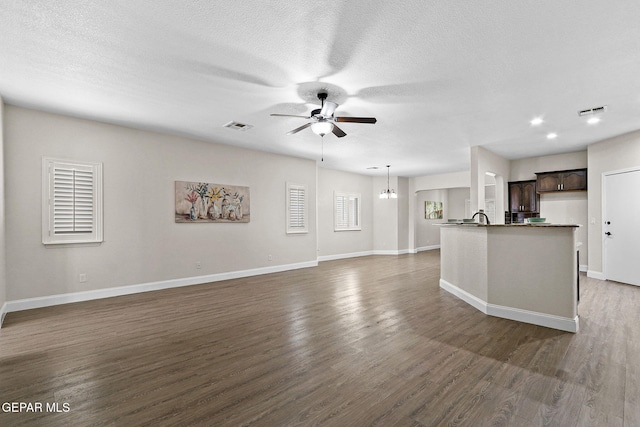 unfurnished living room with baseboards, a ceiling fan, wood finished floors, and visible vents
