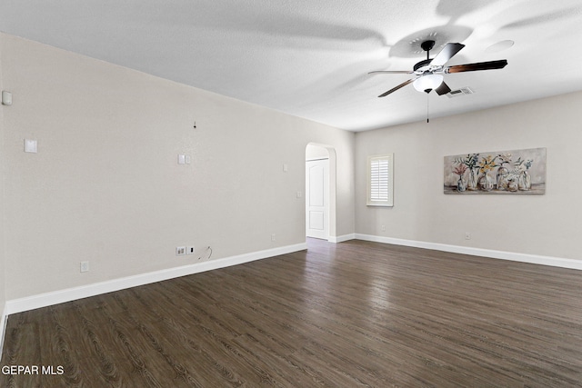 unfurnished room featuring ceiling fan, arched walkways, baseboards, visible vents, and dark wood-style floors