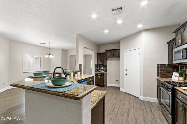 kitchen with backsplash, visible vents, wood finished floors, dark brown cabinets, and stainless steel appliances