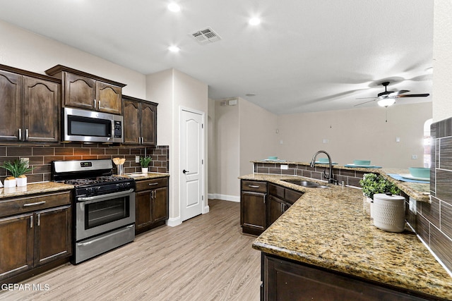 kitchen with visible vents, dark brown cabinetry, tasteful backsplash, a sink, and appliances with stainless steel finishes