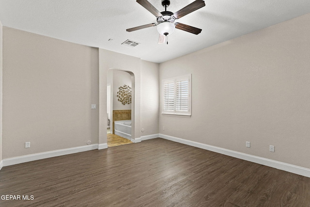 empty room with arched walkways, ceiling fan, baseboards, and dark wood-style flooring