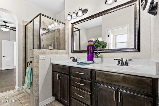 bathroom featuring double vanity, a sink, ceiling fan, and a shower stall