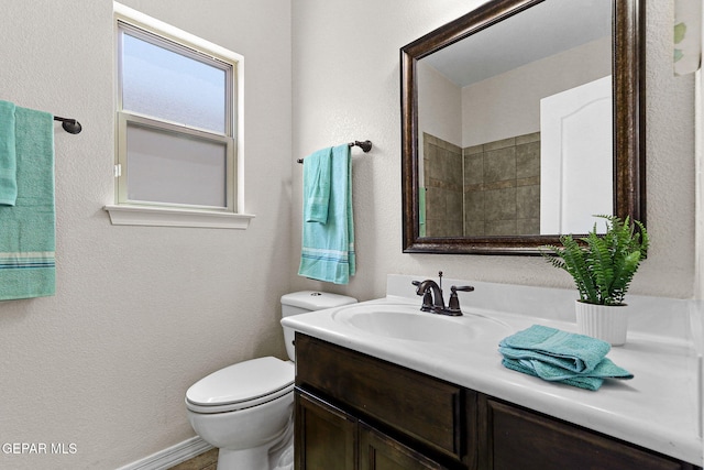 bathroom with toilet, a textured wall, and vanity