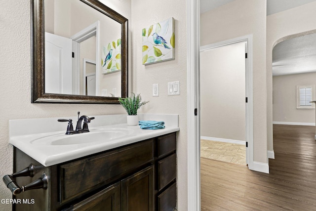 bathroom with baseboards, a textured wall, wood finished floors, and vanity
