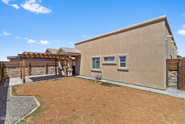 back of house featuring a patio, a pergola, a fenced backyard, and stucco siding