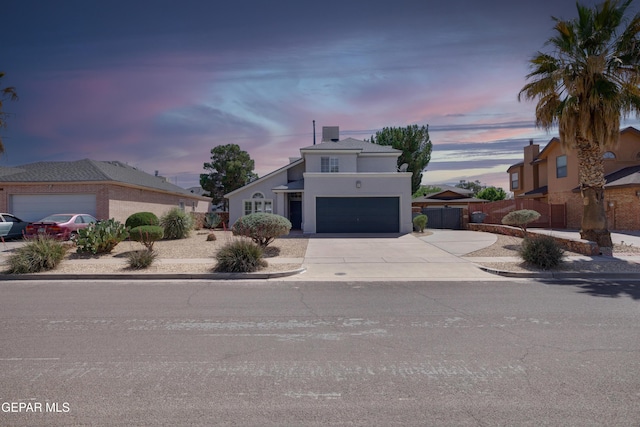 mid-century inspired home with concrete driveway, an attached garage, fence, and stucco siding