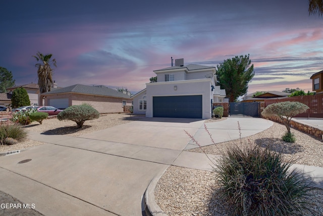view of front of home featuring concrete driveway, an attached garage, fence, and stucco siding