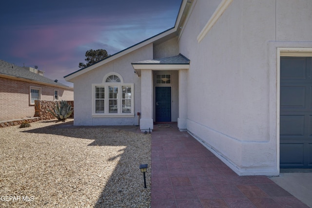 exterior entry at dusk featuring a patio and stucco siding