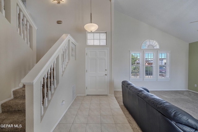foyer entrance featuring high vaulted ceiling, light carpet, and baseboards